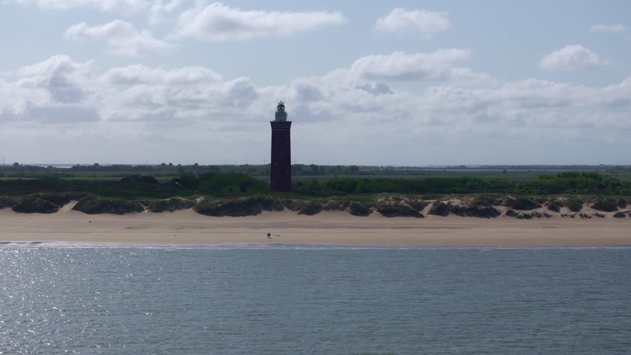 Vista aerea del classico faro di Westhoofd circondato da vaste dune e una spiaggia incontaminata lungo la costa del Mare del Nord vicino a Ouddorp, Paesi Bassi
