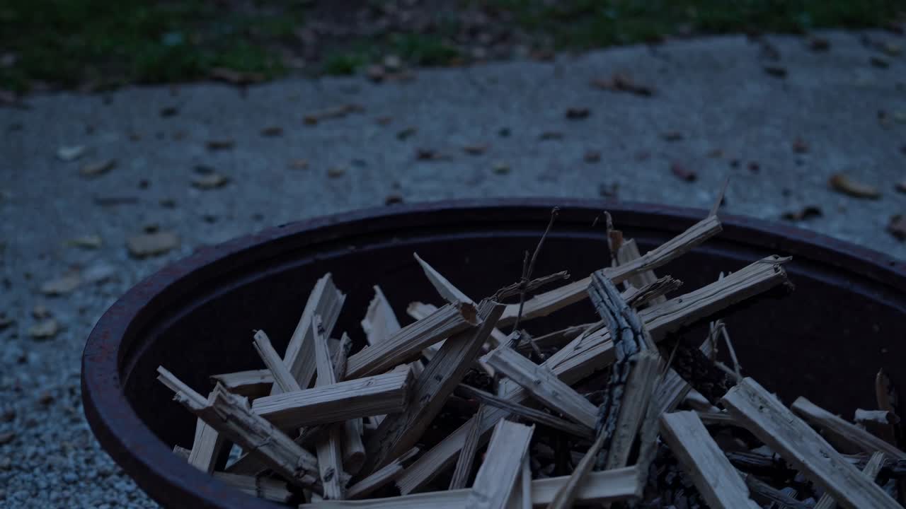 Low-angle video shot of a fire pit filled with kindling, capturing a rustic, outdoor ambiance