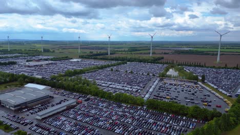 large parking lot full of cars near a wind farm and countryside in germany. marvelous aerial view flight static tripod hovering drone