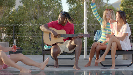 amigos diversos felices con bebidas tocando la guitarra en una fiesta en la piscina en cámara lenta