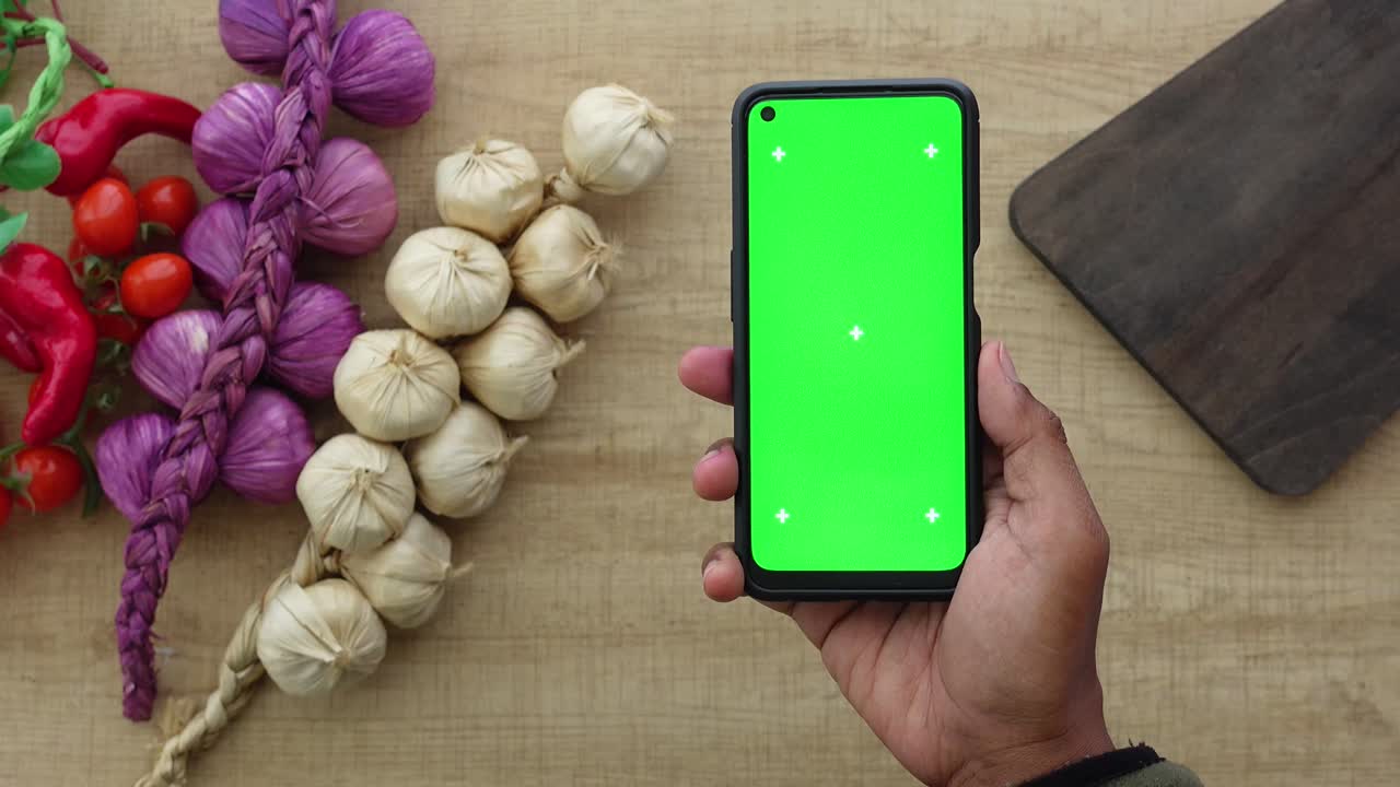 Smartphone with green screen on wooden background with vegetables