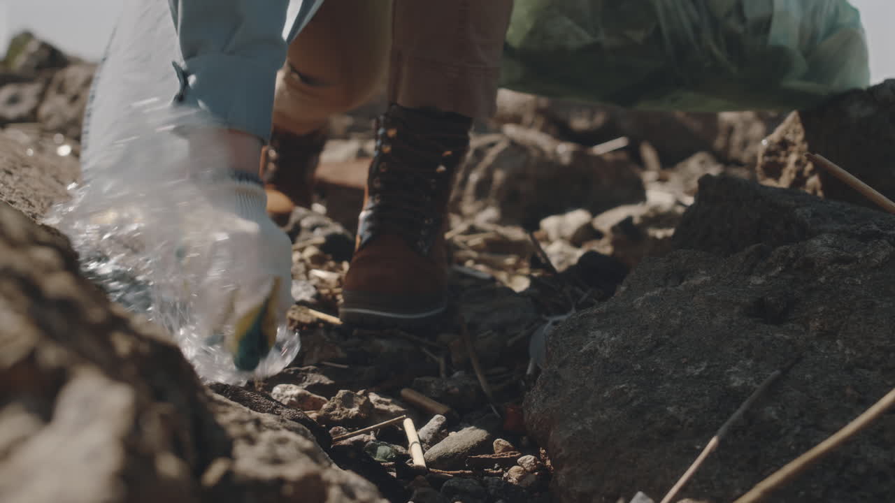 Environmental Activist Walking on Rocky Shore and Collecting Plastic