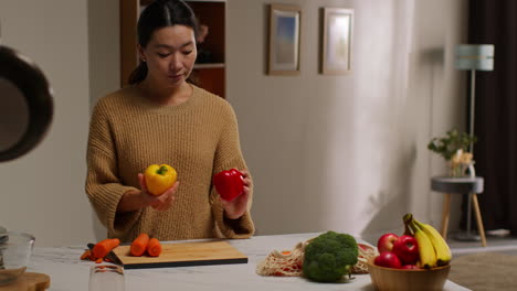 woman at home in kitchen preparing healthy fresh vegetables for vegetarian or vegan meal checking ingredients on board