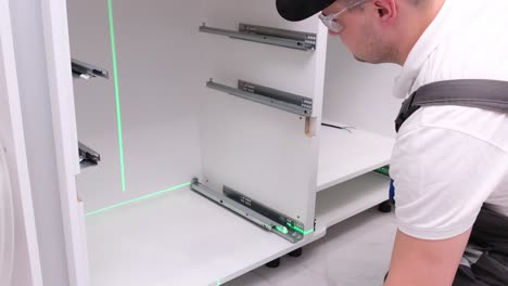 a man using a laser level to install a drawer in a kitchen cabinet apartment renovation concept