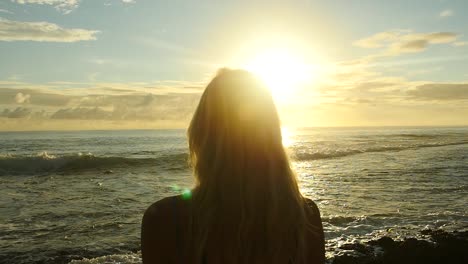 woman from behind watching the sunset and the ocean in french polynesia.