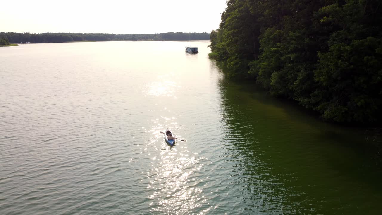 persona montando una canoa en un lago junto a un bosque en brandeburgo, alemania