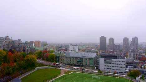 drone moving up, over a synthetic soccer field in the middle of the city on a foggy fall morning in montreal