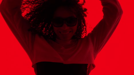 woman with curly hair and sunglasses in red silhouette