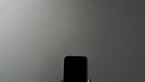 video del monstruo verde de halloween con la mano sujetando un teléfono inteligente con espacio de copia en un fondo gris