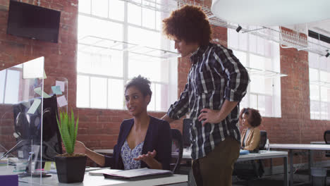 Diverse-male-and-female-colleagues-discussing-over-computer-screen-in-office