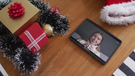 Smiling-caucasian-woman-drinking-coffee-on-christmas-video-call-on-tablet