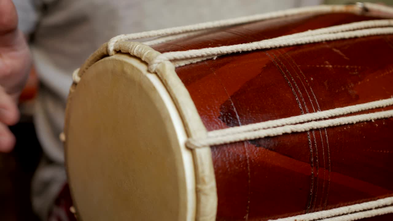 Close up of hands of a man playing a drum.