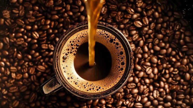 Top-Down-Videoaufnahme, wie Kaffee in eine Tasse gegossen wird, die von Bohnen umgeben ist, wobei der reiche Geschmack hervorgehoben wird