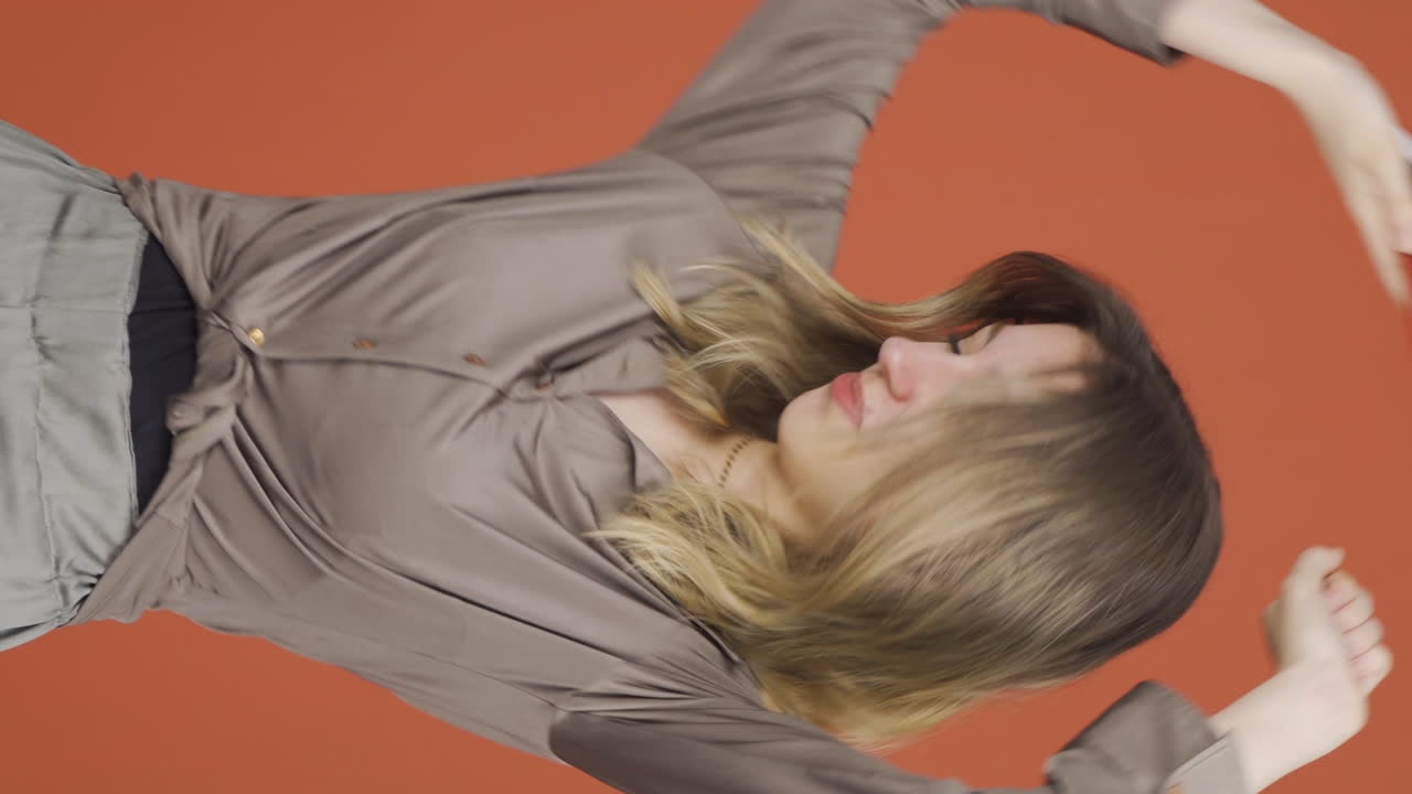 손에  ⁇ 드폰을 들고 춤추는 젊은 여성의 수직 비디오.