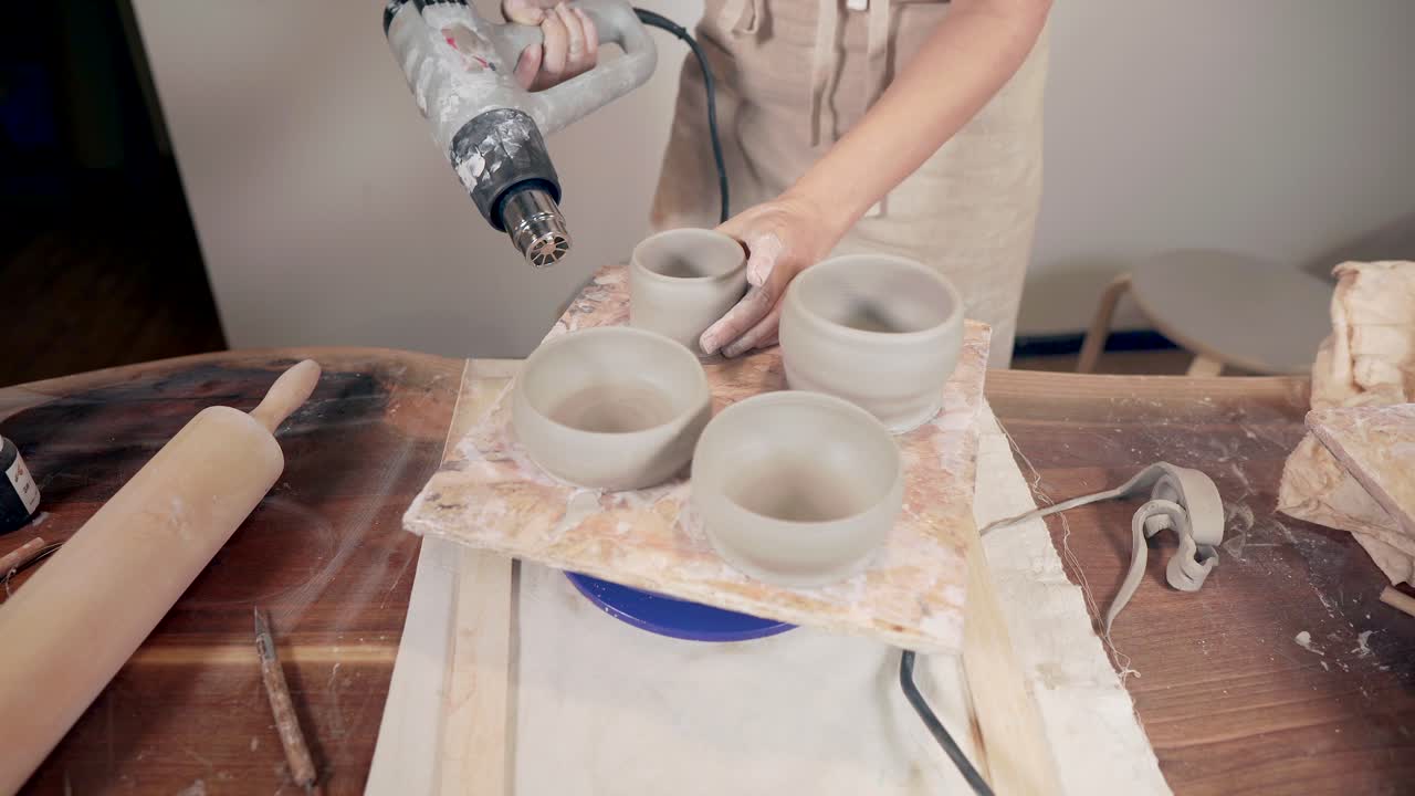 여자 가 뜨거운 공기 총 으로 도자기 그 을 발사 하고 있다