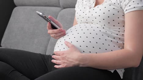 pregnant woman on sofa using phone