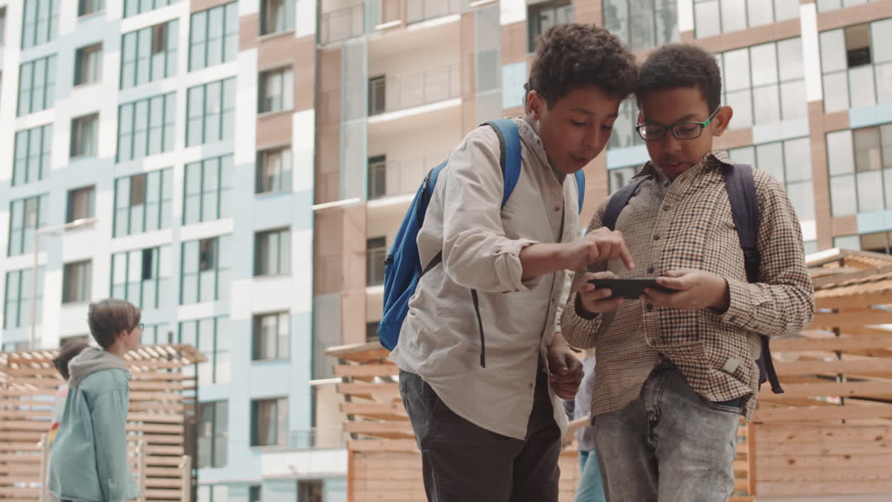 Schoolboys Playing Games on Smartphone Outdoors