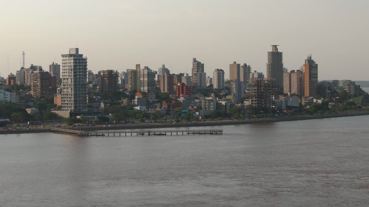 Aerial wide shot showing traffic on coastal road in Posadas City with high-rise buildings at sunset time,Argentina