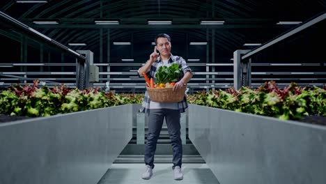 cuerpo lleno de granjero masculino asiático con canasta de verduras que muestra parada, un gesto de mano de pie en la granja inteligente