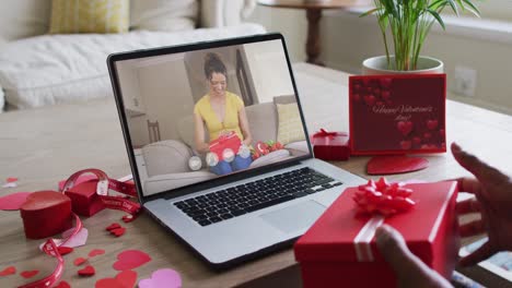 Fröhliche-Gemischtrassige-Frau,-Die-Ein-Geschenk-öffnet-Und-Einen-Videoanruf-Zum-Valentinstag-Auf-Dem-Laptop-Tätigt