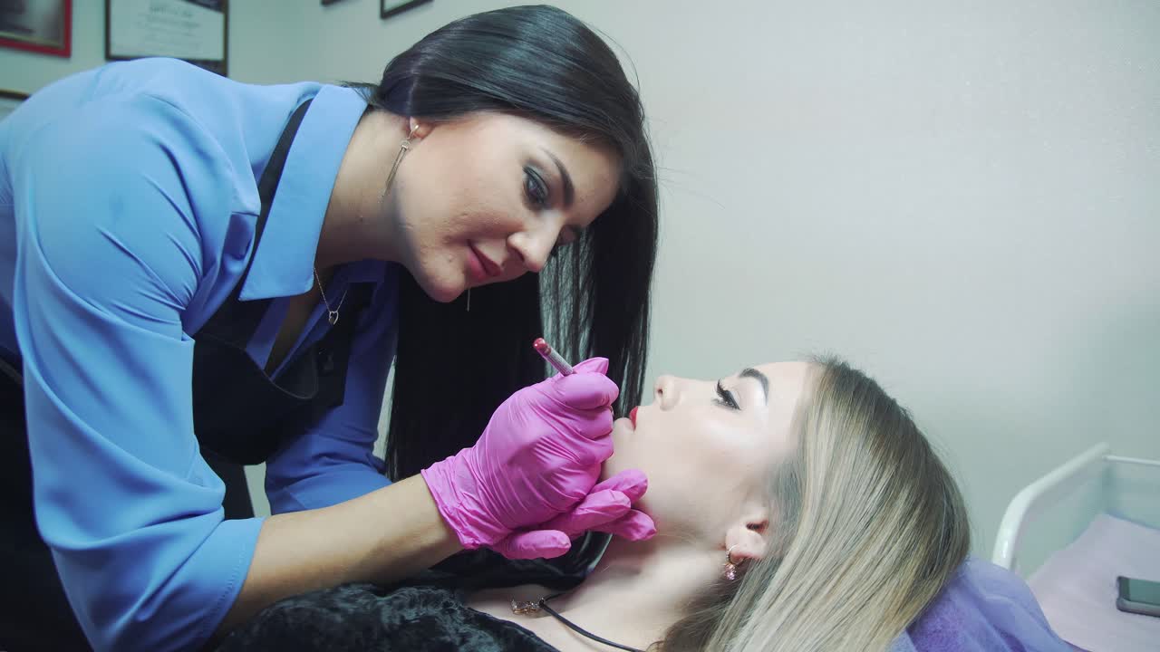 Permanent lip makeup in a beauty salon. A beautician in rubber gloves paints lips