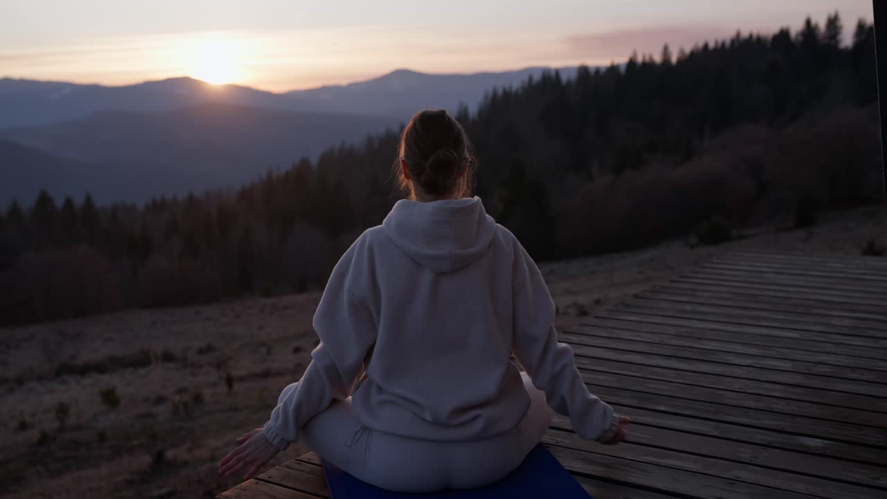 Woman doing yoga in the mountains at sunset