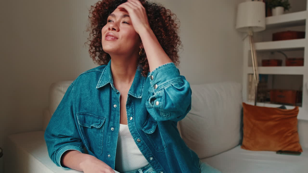 Content Young Woman with Curly Hair Smiling on Sofa