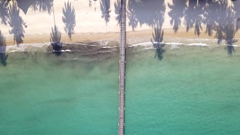 Vista-Aérea-De-Arriba-Hacia-Abajo-De-La-Hermosa-Playa-De-Arena-Blanca-Con-Palmeras-Volando-Hacia-El-Embarcadero