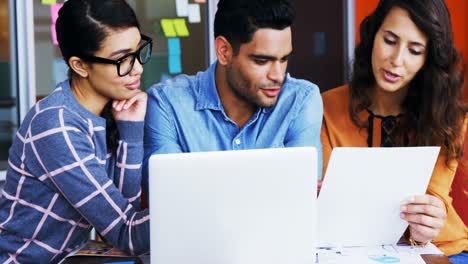 diseñadores gráficos sonrientes discutiendo sobre la computadora portátil en una reunión
