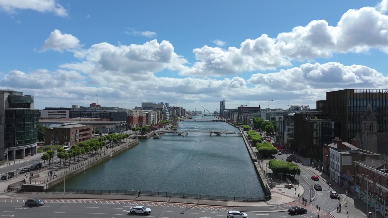 Die Kamera gleitet über den Uferkorridor Dublin June26 und offenbart mehrere Straßen- und Fußgängerüberwege unter verstreuten Sommerwolken