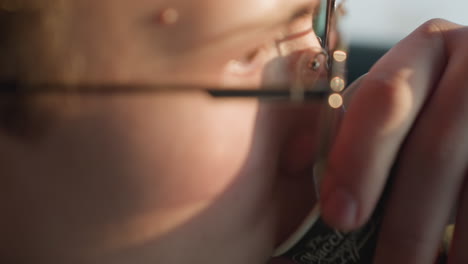 close-up of a young boy sipping a drink, with sunlight beautifully reflecting off his face, capturing a serene and thoughtful moment against a softly blurred background