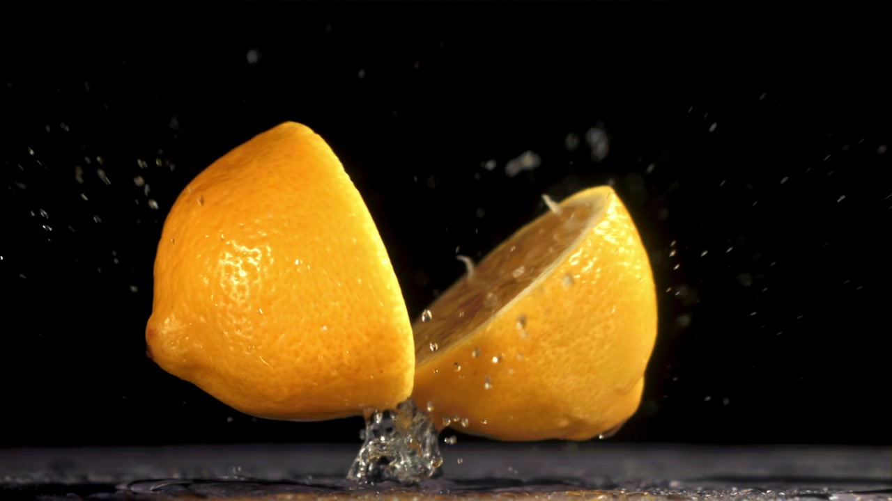 Limone fresco che cade e si divide al rallentatore con uno schizzo d'acqua