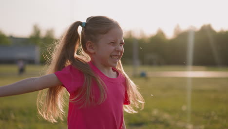 happy little girl waves off flying fluffs on spring meadow