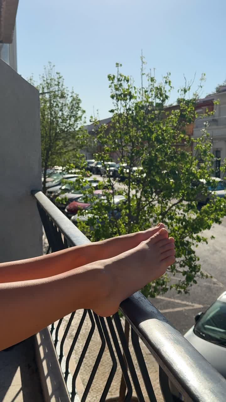 Feet Relaxing on a Balcony Railing with City View