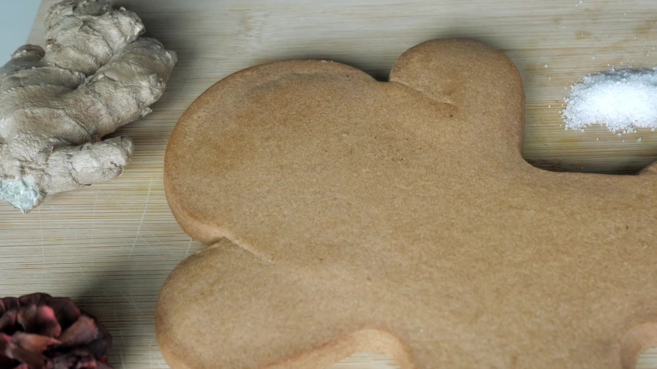 Grande biscotto di pan di zenzero su tagliere di legno con ingredienti intorno.