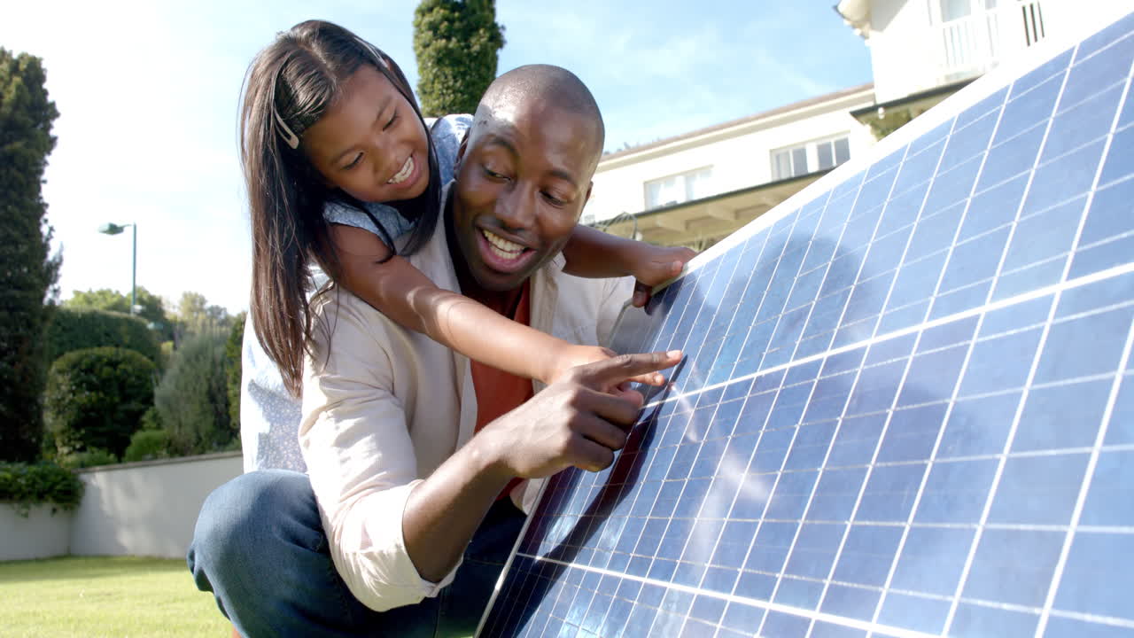 Father and daughter examining solar panel together, learning about renewable energy