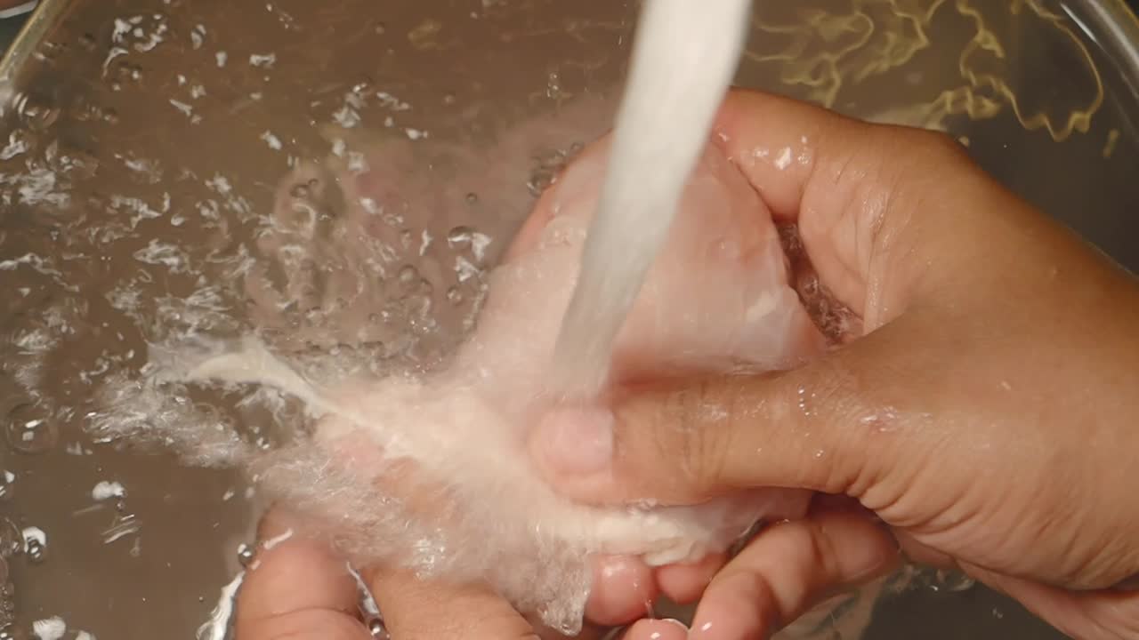 Hands washing food under running water