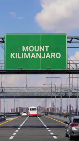 highway sign to mount kilimanjaro with airplane in the sky