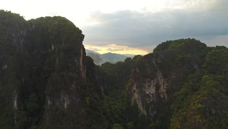 aerial. increíble video de estilo cinematográfico de enormes montañas y selva tropical en el sur de tailandia. vuelo de drones a través del pico. llamaradas solares detrás de las montañas. vuelo de dos pájaros cerca del cuadrocóptero.