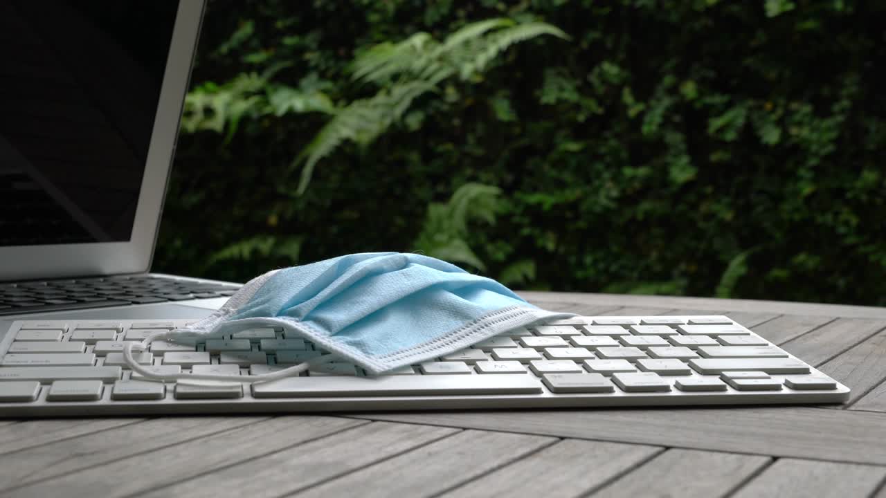 한 여성이 의료용 얼굴 마스크를 들고 드폰을 테이블 위에 놓았습니다.