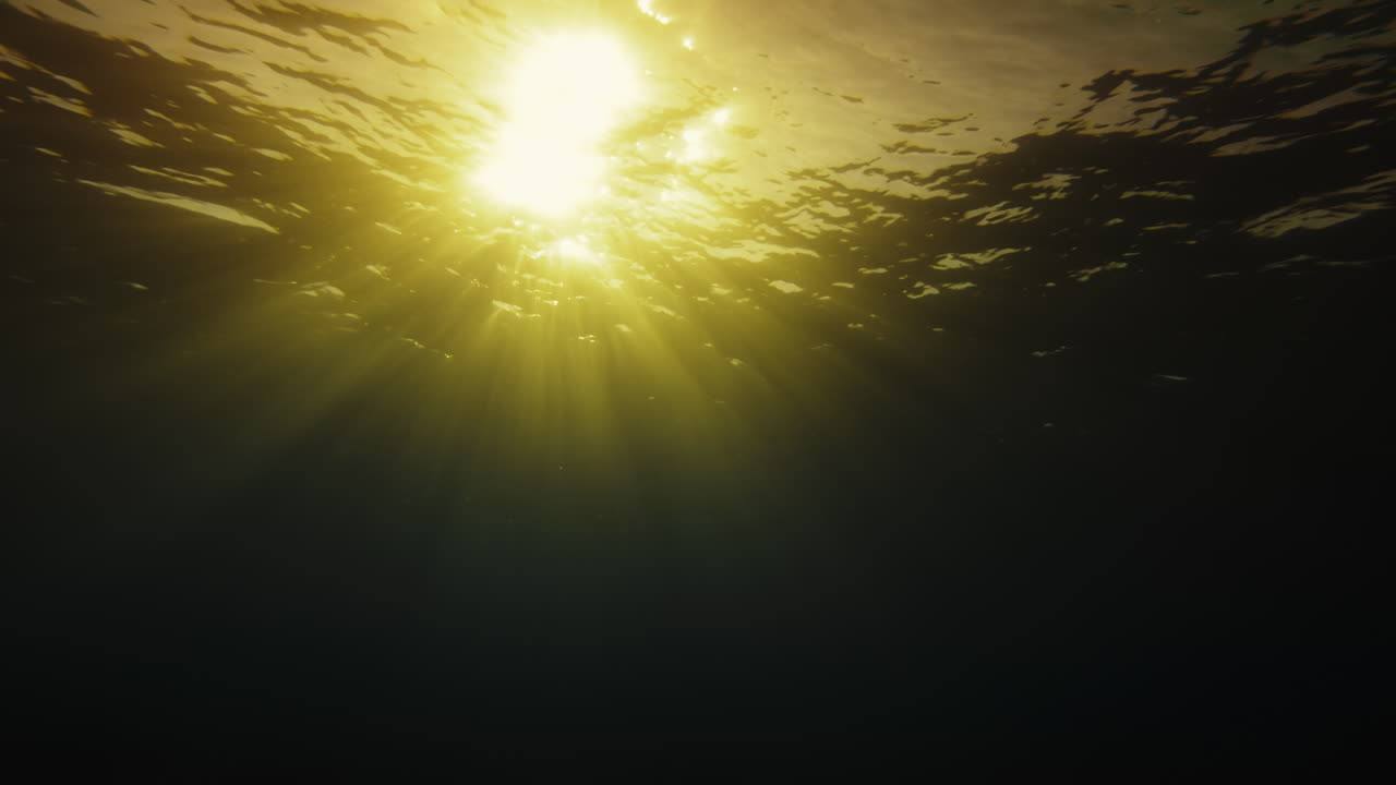 Beams of Light Cross the Surface of the Sea at Sunset Underwater
