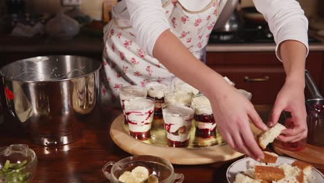 woman making layered dessert parfaits in the kitchen