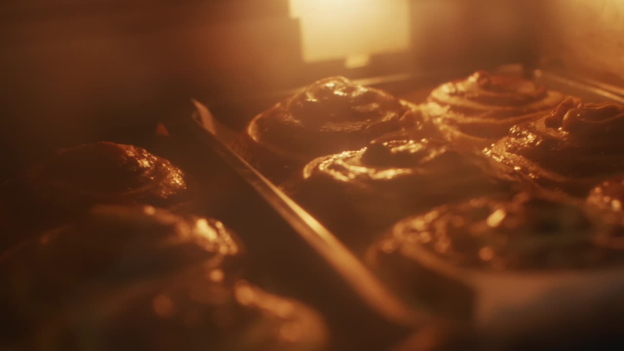 Bakers dozen of cinnamon rolls baking in over, filmed as handheld close up shot