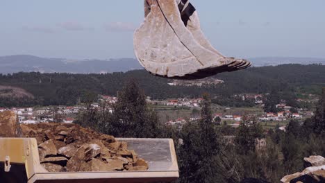 Baggerschaufel-Schwebt-über-Felsen-Vor-Einer-Malerischen-Kulisse