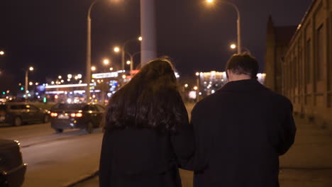 rear view of a couple hugging while they walking in the street after the new year's party