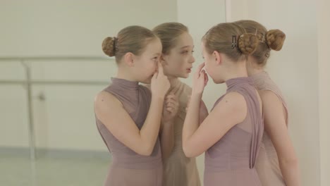 un grupo de jóvenes estudiantes de ballet con ropa de baile negra practicando posiciones en un amplio estudio de ballet con pisos de madera y barras montadas en la pared. expresiones enfocadas y movimientos sincronizados.
