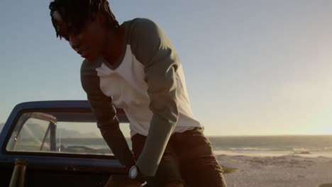 Man-sitting-on-trunk-of-pickup-truck-at-beach-4k