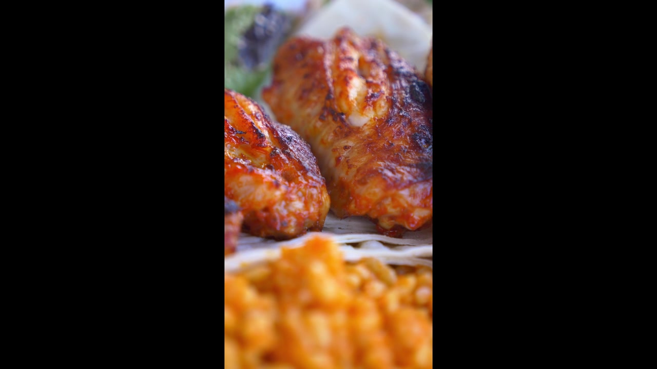 Primo piano di ali di pollo grigliate servite con riso e verdure