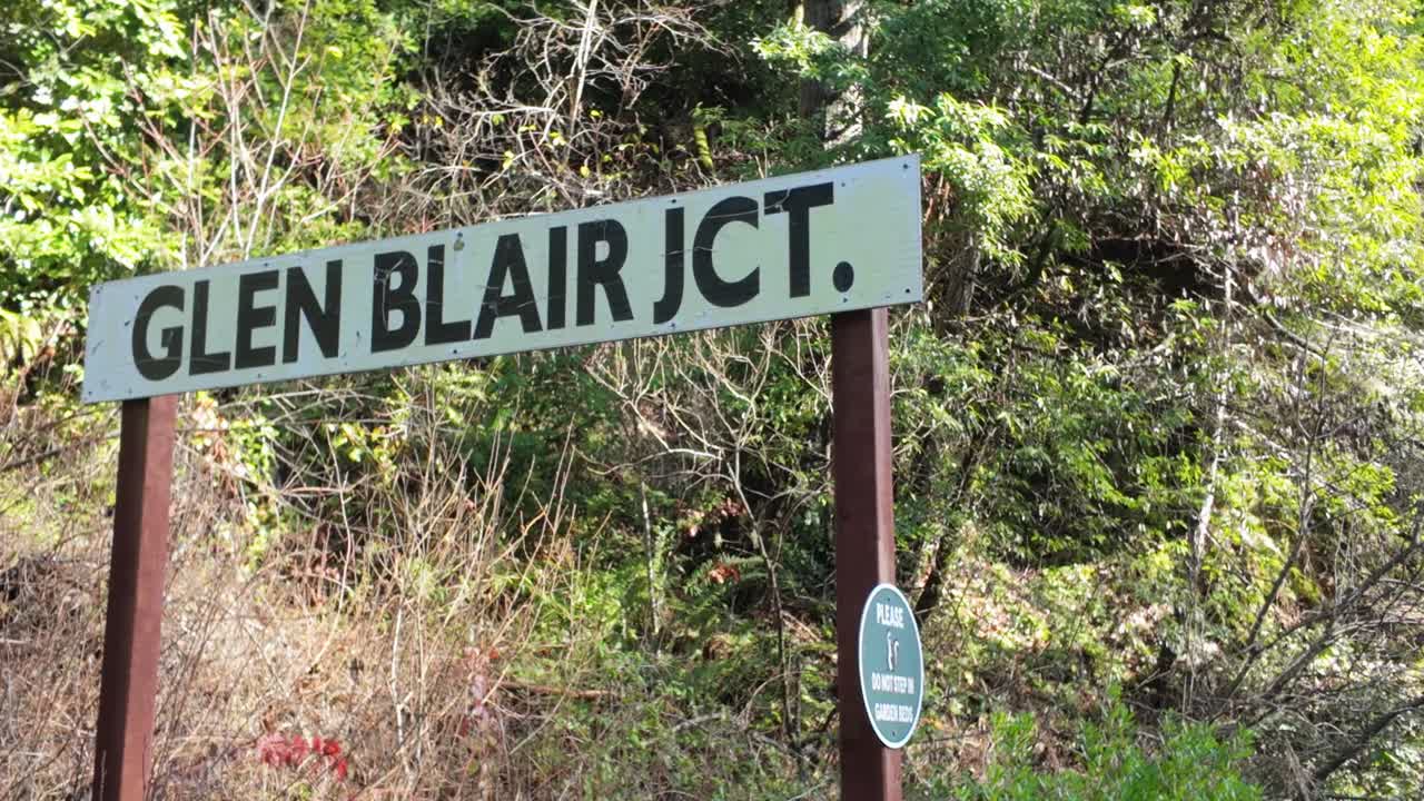 Gimbal close-up panning shot of the Glen Blair Junction sign at a redwood forest in Northern California. 4K