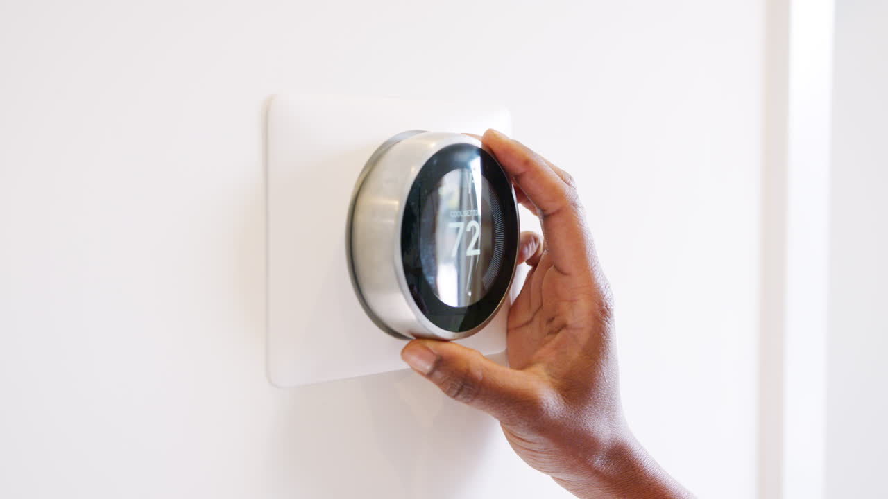 un primer plano de una mujer configurando un termostato de calefacción inteligente en casa